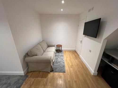 a living room with a couch and a flat screen tv at Lower Stondon Studio in Stondon