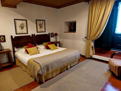 a bedroom with a bed with yellow and red pillows at Casa de Santa Ana da Beira in Seia