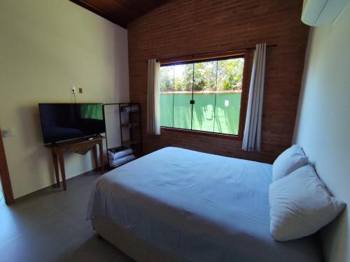 a bedroom with a bed and a window and a television at Loft BeiraMar 2 in Serra