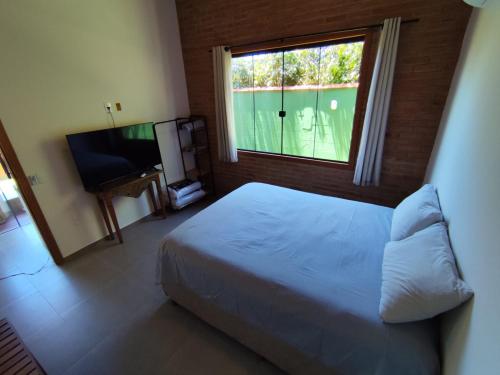 a bedroom with a bed and a window and a television at Loft BeiraMar 2 in Serra