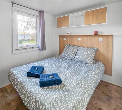 2 sacs bleus assis sur un lit dans une chambre dans l'établissement L'orchidée des bois, à Litteau