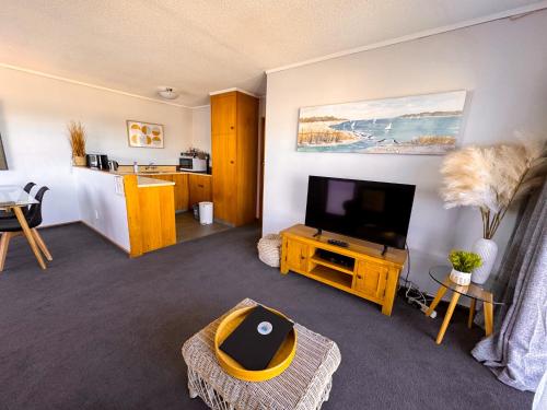 a living room with a flat screen tv and a couch at Waikanae Beach Motel in Gisborne