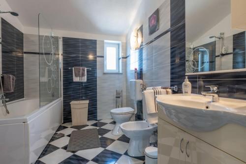 y baño con lavabo, aseo, bañera y lavamanos. en Villa Sandra, a beautiful villa with sea view and a pool, en Drenje