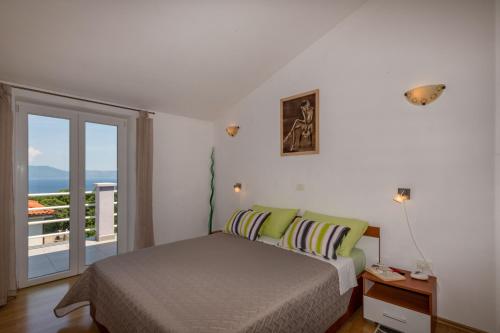 Un dormitorio con una cama y un balcón. en Villa Sandra, a beautiful villa with sea view and a pool, en Drenje