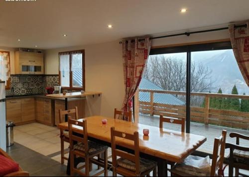 une cuisine et une salle à manger avec une table et une grande fenêtre dans l'établissement chalet la Dalle, à Saint-Martin-de-la-Porte