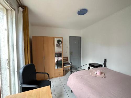 une chambre avec un lit, une chaise et une fenêtre dans l'établissement Maison de Longde - chambre, à Villejuif