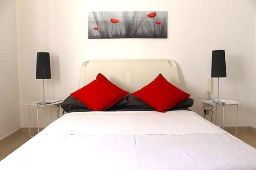 a white bed with two red pillows in a bedroom at La Villa in Salve