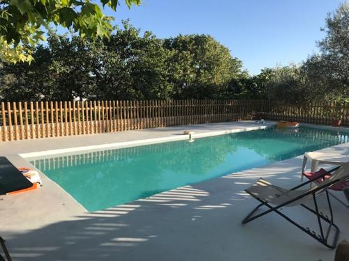 - une piscine avec une chaise et une clôture dans l'établissement Grande Maison avec Piscine, juillet et août, Jardin Privatives à NYONS, à Nyons