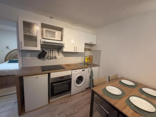 a kitchen with a table and a room with a bed at La cachette audomaroise avec sa terrasse in Saint-Omer