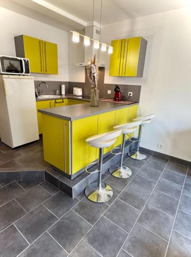 une cuisine avec des placards jaunes et un comptoir avec des tabourets dans l'établissement Appartement terrasse - 50m plage, à Canet