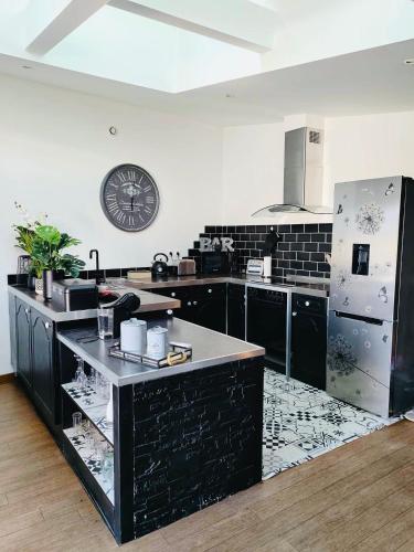 une cuisine avec des armoires noires et une horloge murale dans l'établissement LOFT Aux Retrouvailles -Gîte avec Spa De 2 à 6 personnes, à Moriviller