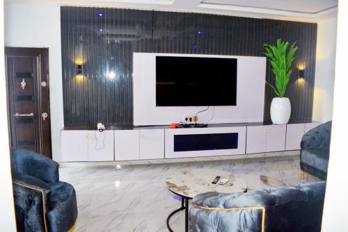 a living room with a tv and two chairs and a table at Ike Service Apartments in Owerri