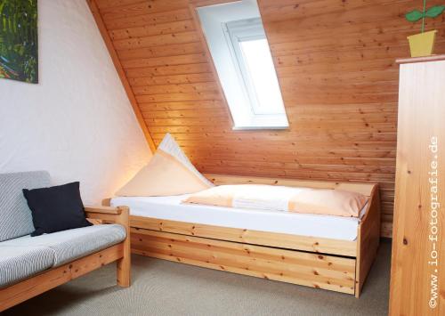 a bed in a wooden room with a window at Kleine Brise mit Meerblick und Schwimmbad in Kronsgaard