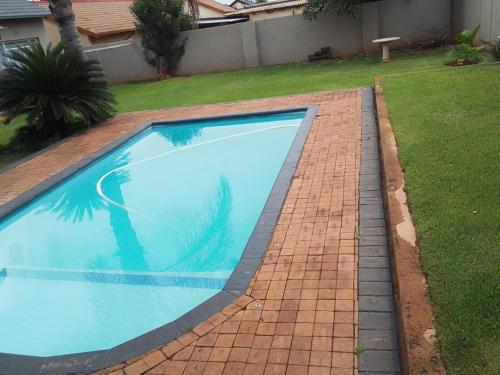 a swimming pool in a yard with a brick sidewalk at Falconbridge Properties in Krugersdorp