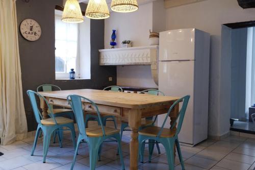 une cuisine avec une table et des chaises en bois et un réfrigérateur dans l'établissement L'Orée des Vignes, à Montcaret
