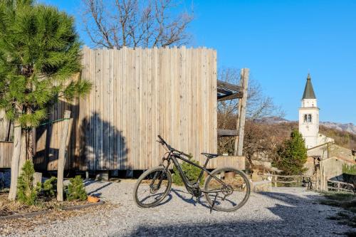 a bike parked next to a fence and a church at Panorama glamping Vipavska dolina in Dobravlje