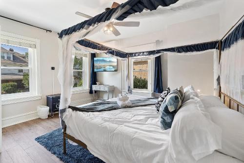 a bedroom with a canopy bed and windows at Main Line Manor 3BR with King Beds & Patio & Backyard in Bryn Mawr