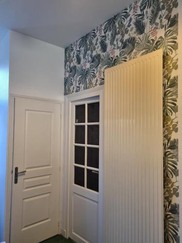 une pièce avec une porte blanche et du papier peint à fleurs dans l'établissement Logement indépendant Sacré Coeur, à Cholet