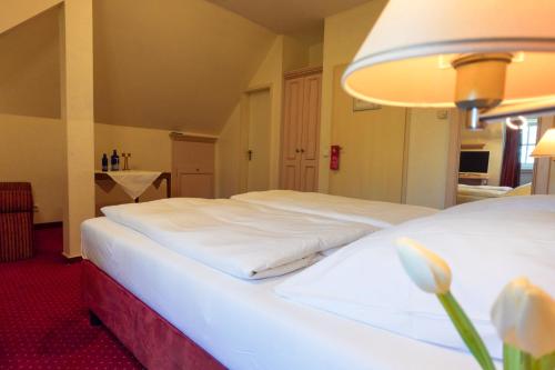 a hotel room with two beds with white sheets at Hotel Casino im Park in Kamp-Lintfort