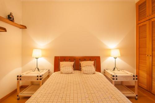 a bedroom with a bed with two lamps on it at Oceanos premium apartment in Ovar