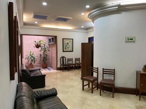 a waiting room with a leather couch and chairs at Hotel Casa Santa Monica Norte in Cali