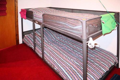 Ce dortoir comprend 2 lits superposés et un tapis rouge. dans l'établissement Résidence Les Tavaillons - 208 Les Tavaillons Studio pour 4 personnes MAE-8861, aux Orres