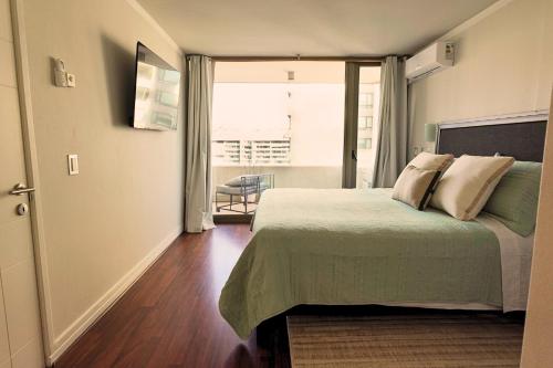 a bedroom with a bed and a large window at Depto a pasos del Parque Arauco con Aire Acondicionado in Santiago