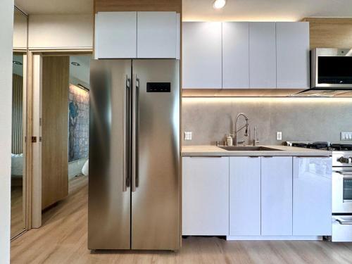 a stainless steel refrigerator in a kitchen with white cabinets at Titus Retreat in San Diego