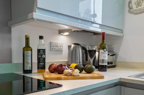 a kitchen with bottles of wine and vegetables on a cutting board at Substantial 5 bedroom townhouse with disabled access apartment, private off road parking space with EV point from 15th April 26, jaccuzi bath, Netflix and Wifi, near Argyle, boutique shops eateries and pubs in Plymouth