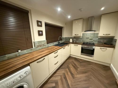 a kitchen with white cabinets and a wooden floor at Ruby Sands in Saltburn-by-the-Sea