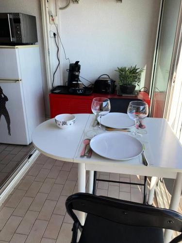 - une table blanche avec deux verres à vin dans l'établissement Résidence Port Soleil Bâtiment B3 - Studio Cabine 2 pers. Port Soleil CAP d'AGDE MAE-4424, au Cap d'Agde