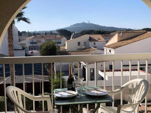 - une table et des chaises sur un balcon avec une bouteille de vin dans l'établissement Résidence Port Soleil Bâtiment B2 - Studio 3 pers- Port Soleil 2ième étage MAE-4464, au Cap d'Agde