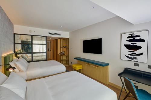 a hotel room with two beds and a desk at Hotel Indigo Lima Miraflores by IHG in Lima