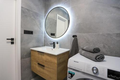 a bathroom with a sink and a mirror and a washing machine at Moderný apartmán Považská Bystrica - Centrum in Považská Bystrica