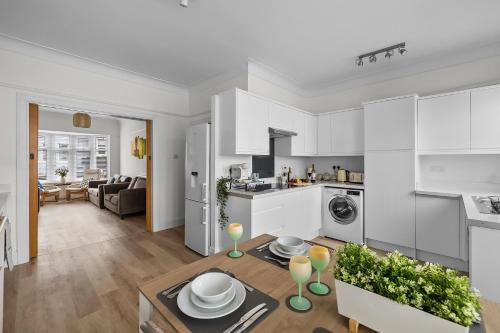 eine Küche und ein Wohnzimmer mit weißen Schränken in der Unterkunft Townhouse with modern mobility accessible apartment including widened doors and ramps, pets welcome, 5 bedrooms, secure off road parking, near Home Park, golf, pitch and putt, tennis courts, Argyle, eateries, microbrewery, pubs, boutique shops and salons in Plymouth