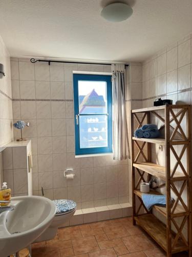 a bathroom with a sink and a toilet and a window at Wieck - Ferienwohnung EVA & HANSI by Restaurant WIESENAU in Wieck