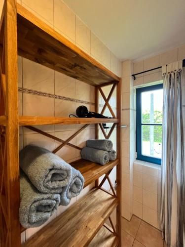 a bathroom with wooden shelves with towels and a window at Wieck - Ferienwohnung EVA & HANSI by Restaurant WIESENAU in Wieck