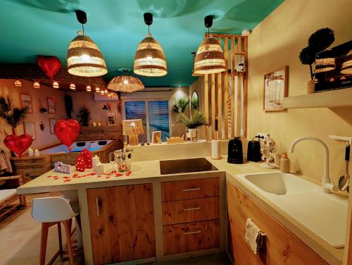 a kitchen with a sink and a counter with hearts on the wall at Les Spas de la Mer, Appart&Spa Aloha, 100m de la plage, Plein cœur du Grau in Le Grau-du-Roi