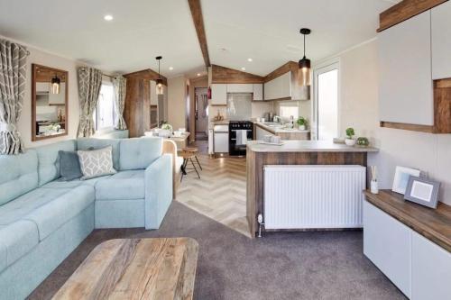 a living room with a blue couch and a kitchen at Lakeside Retreat - AGH Hot Tub Breaks - Tattershall Lakes in Tattershall