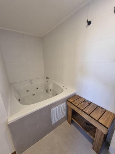 a white bathroom with a tub and a wooden bench at Maré Hotel Boutique in Viña del Mar