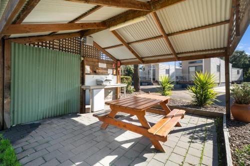 a patio with a wooden picnic table and a kitchen at Shepparton Holiday Park and Village in Shepparton