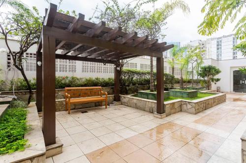 a wooden bench under a wooden pergola in a garden at Lapa Loft, estúdio vintage com total infraestrutura na Lapa, RJ in Rio de Janeiro