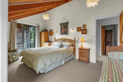 a bedroom with a bed and a table with a lamp at Karearea Cottage - Rural Retreat Purau in Purau