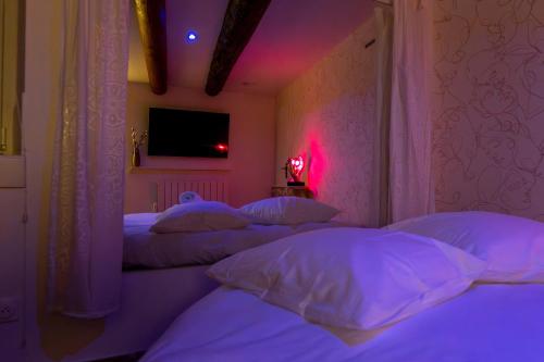 - une chambre avec 3 lits avec des oreillers blancs et une télévision dans l'établissement Love Room l'Eden Secret, à Grans