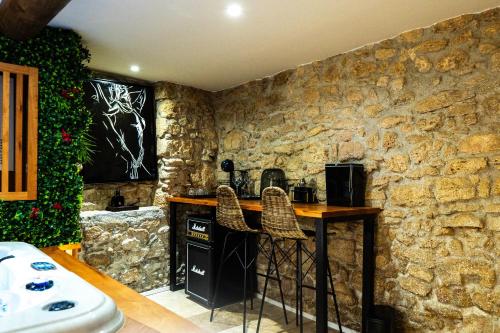 une cuisine aux murs en pierre avec un comptoir et des tabourets dans l'établissement Love Room l'Eden Secret, à Grans