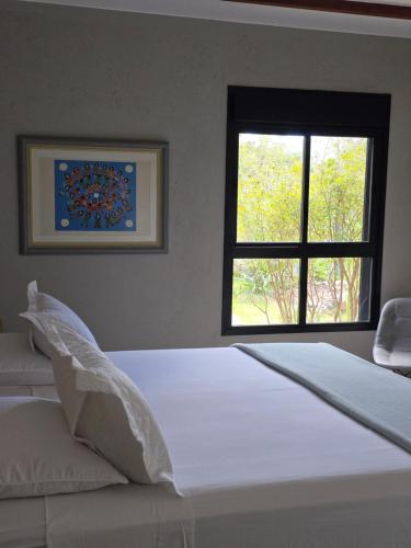 a bedroom with a large bed with a window at Confraria da Prata Flats in Pirenópolis