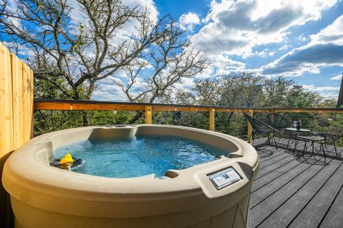 a hot tub on a wooden deck with a table at Ares Treehouse Romantic Hottub Fredericksburg EV in Fredericksburg