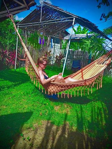a woman sitting in a hammock under an umbrella at HOTEL RENASCI PALOMINO in Palomino