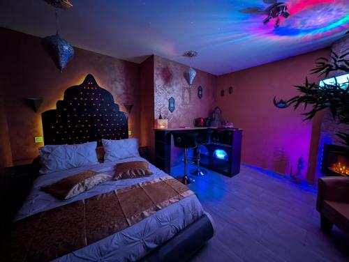 a bedroom with a bed in a room with purple lights at 1000 et une Nuit in La Boissière-de-Montaigu
