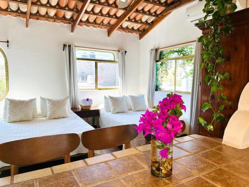 a room with two beds and flowers on a table at CABO BOHEMIA Tropical Garden Studios in Cabo San Lucas
